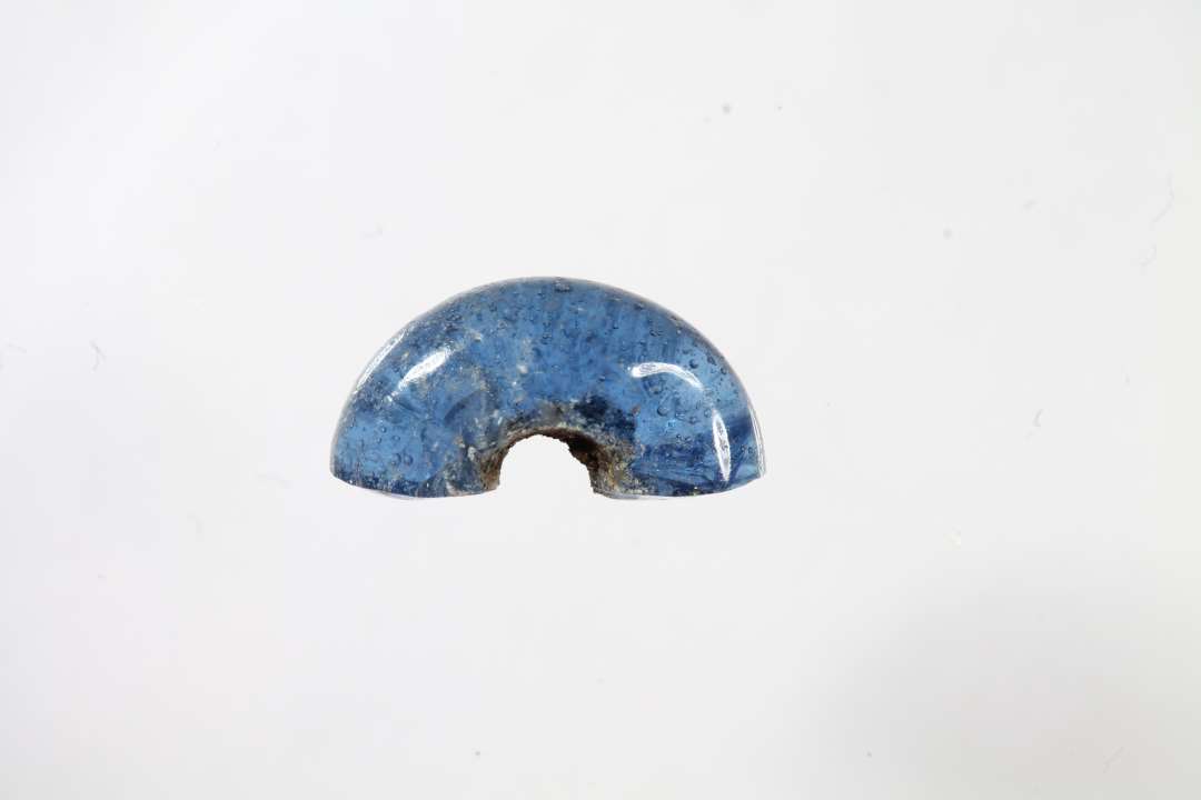 Halv ringformet, gennemsigtig blå glasperle. Diameter: 1 cm.