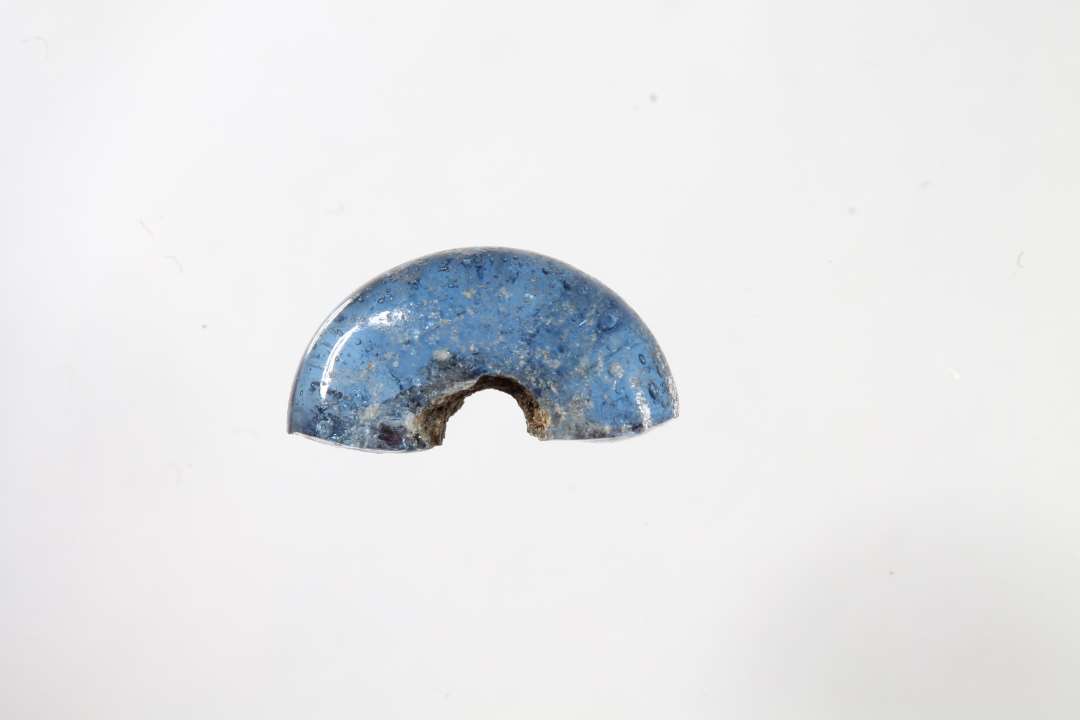 Halv ringformet, gennemsigtig blå glasperle. Diameter: 1 cm.