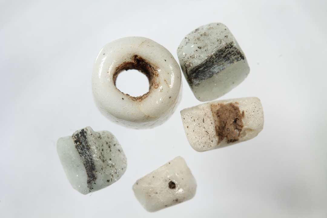 fem fragmenter af cylindriske, uigennemsigtige hvidgrå glasperler