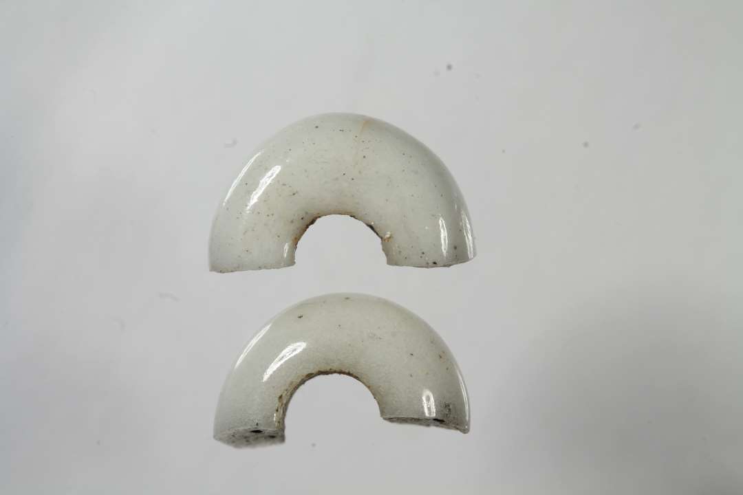 To halve ringformede, uigennemsigtige hvidgrå glasperle, diameter: 1-1,1 cm.