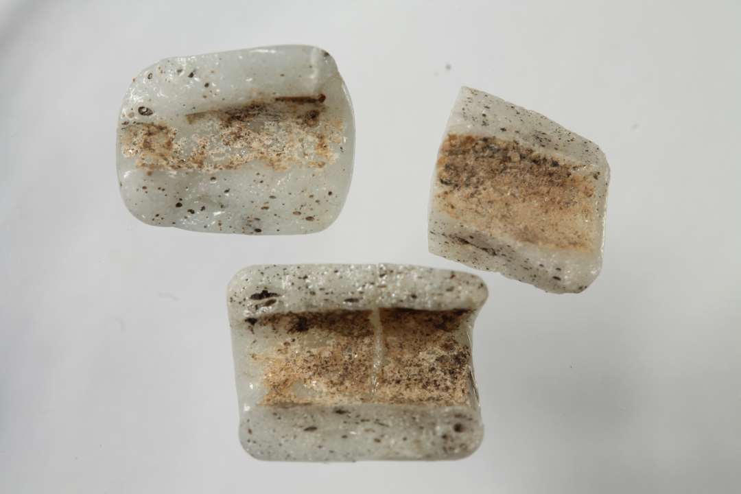 Fire fragmenter af cylindriske, uigennemsigtige, hvidgrå glasperler