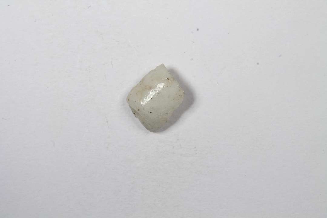 Fragment af cylindrisk, uigennemsigtig hvidgrå glasperle