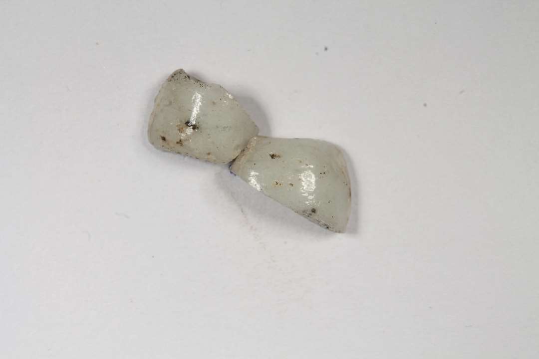 To fragmenter af cylindriske, uigennemsigtige, hvid-grå glasperler, største mål: 0,7-0,9 cm.