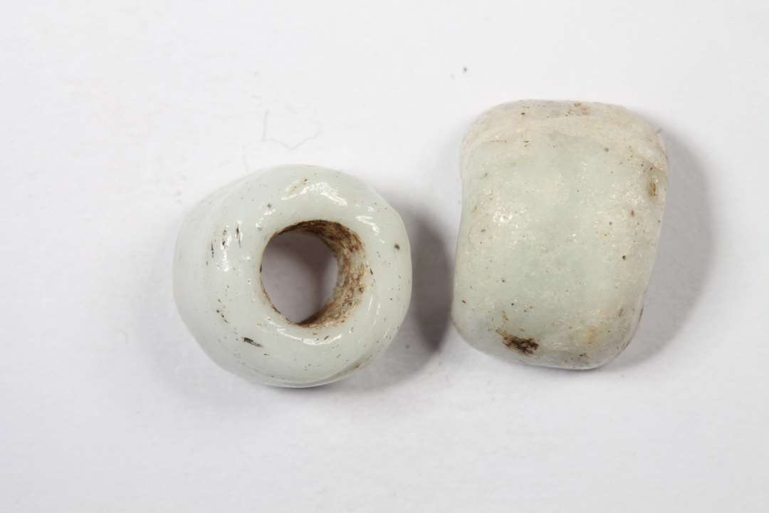 To halve cylindriske uigennemsgtige, hvidgrå glasperler. Diameter: 0,9 og 1 cm.