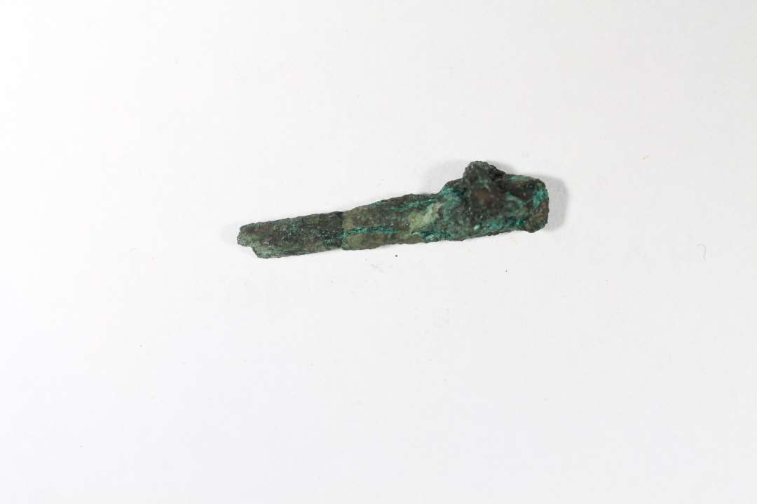 Bronzenål, brækket i to dele. Ornamenteret, profileret hoved med gennemboring og ring. dårligt bevaret. Samlet længde: ca 5,2 cm.