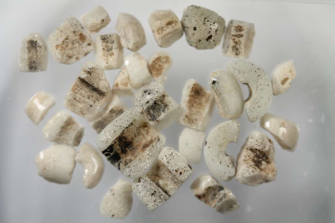 Fem halve cylindriske, uigennemsigtige, hvidgrå glasperler, samt 25 mindre stumper, måske også af ringformede perler