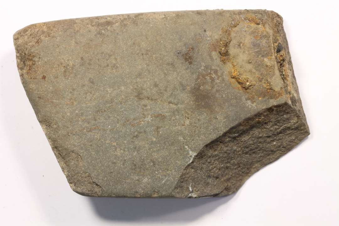 Fragment af hvæssesten af mørkegrå skifer. Mål: 4,6x1,5x7,3 cm.