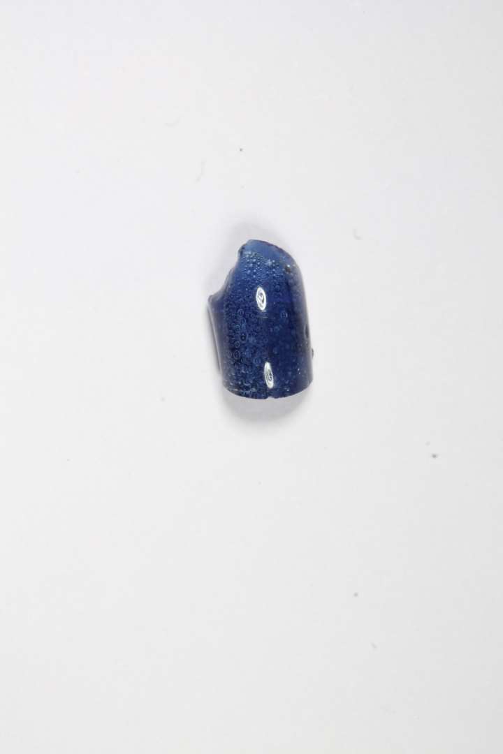 Mindre fragment af ringformet, gennemsigtig, blå glasperle