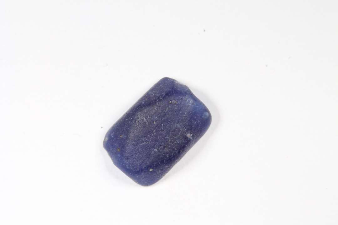 Halv polyedrisk, polyhydrid, halvgennemsigtig blå glasperle. Største mål: 1 cm.