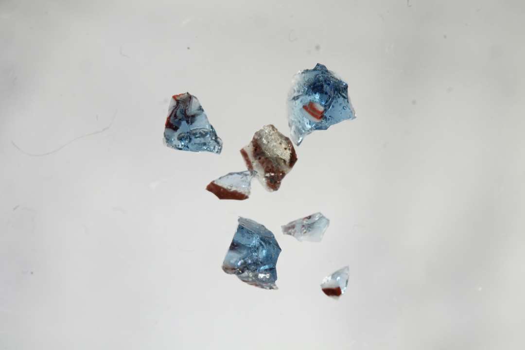 Flere små splinter af gennemsigtig blåt glas med rødt og hvidt