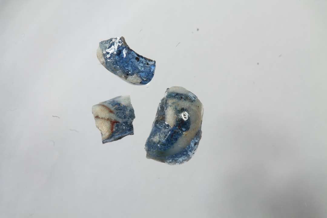 Tre fragmenter af gennemsigtig blå glasperle med hvidt