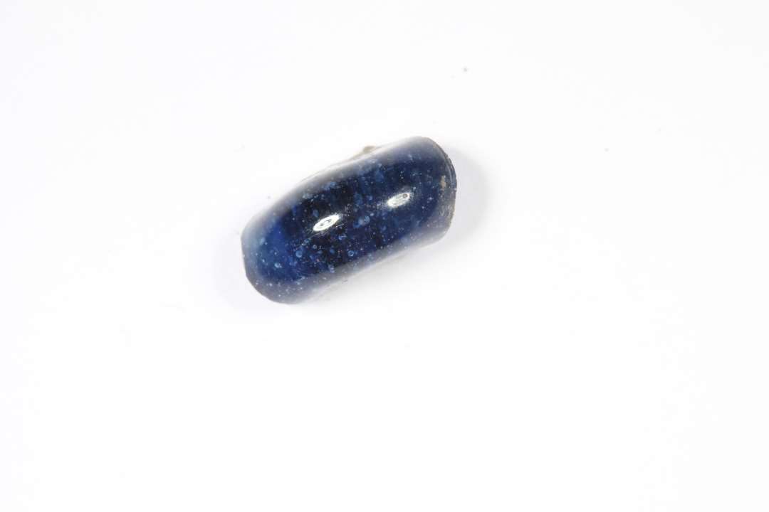 Fragment af ringformet, gennemsigtig blå glasperle. Diameter: ca 1 cm.