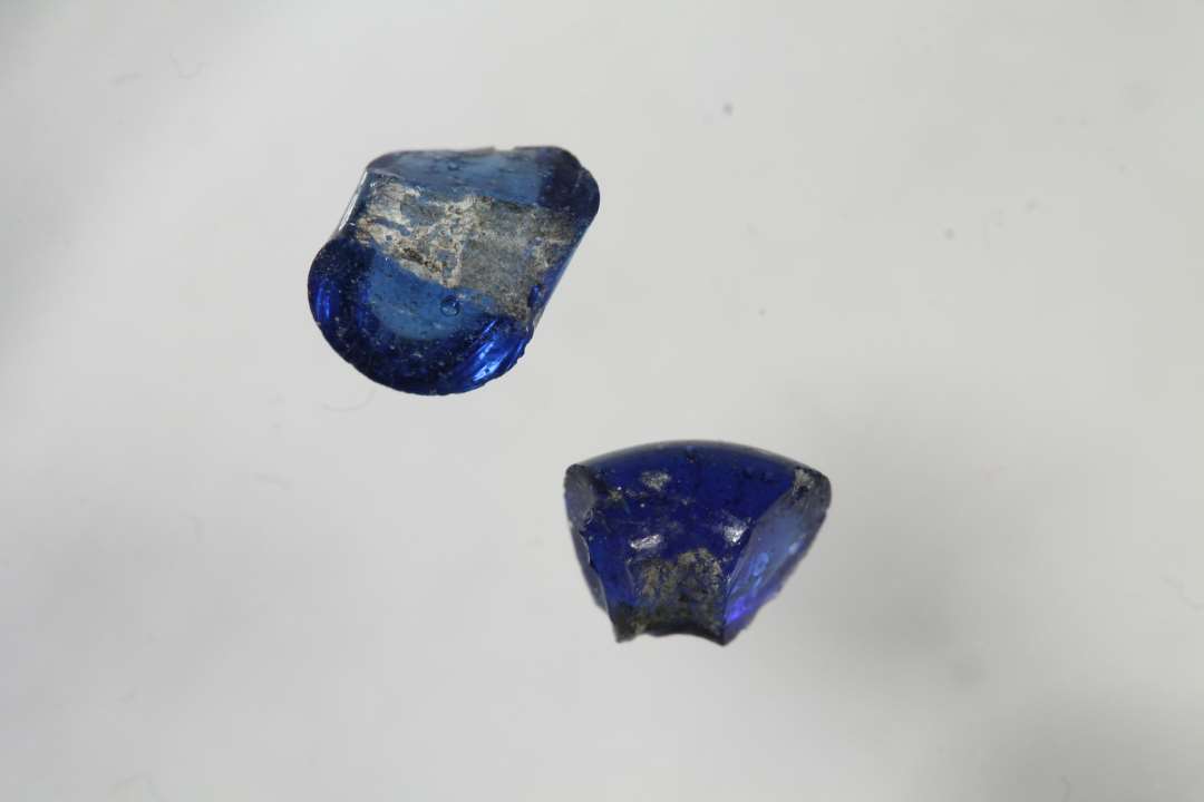 To fragmenter af ringformede, gennemsigtige blå glasperler