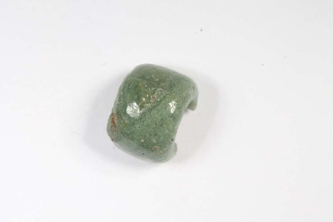 Fragment af ringformet, uigennemsiigtig grøn glasperle. Diameter: 1 cm.