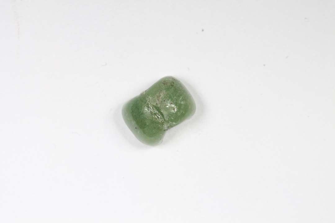 Halv, ringformet, uigennemsigtig grøn glasperle. Diameter: 0,6 cm.