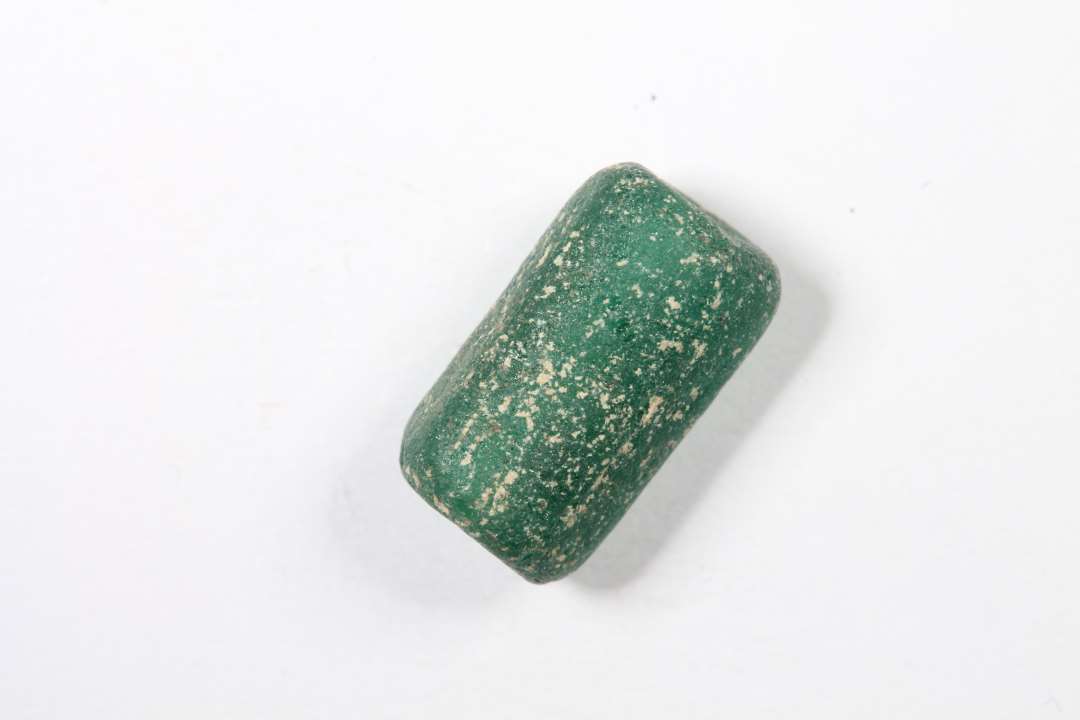 Kubisk cylindrisk, halvgennemsigtig, 6-kantet, grøn glasperle. slidt overflade/kanter. Længde: 1 cm.