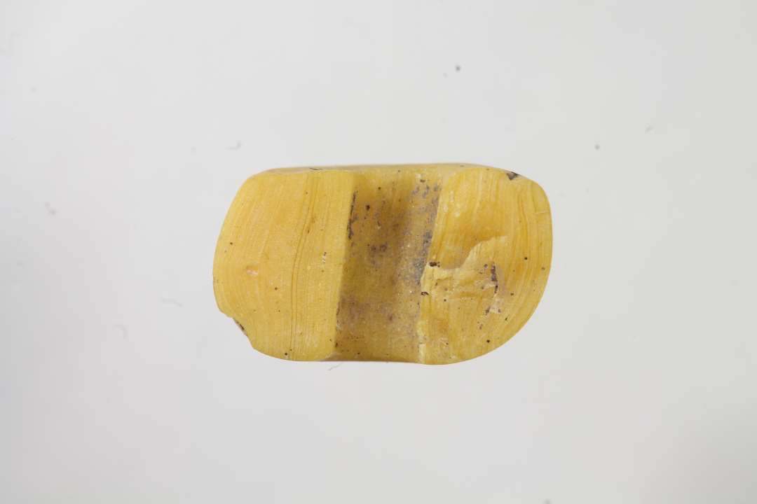 Halv afskåret, ringformet, uigennemsigtig, gul glasperle. Diameter: 1 cm. 