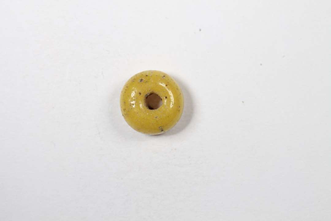 Cylindrisk/ringformet, afskåret, uigennemsigtig gul glasperle. diameter: 0,6 cm.