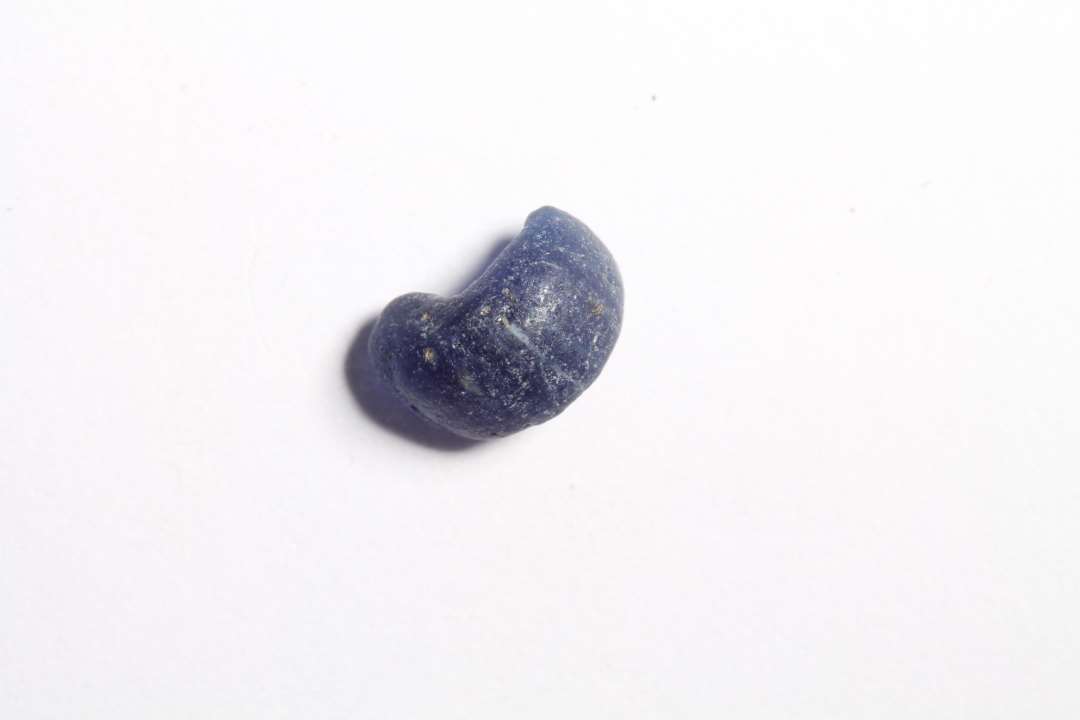 Halv, ringformet, afskåret, halvgennemsigtig blå glasperle. diameter: 0,7 cm.
