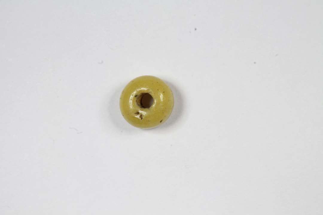 Cylindrisk, afskåret, uigennemsigtig, gul glasperle. Diameter: 0,5 cm. 
