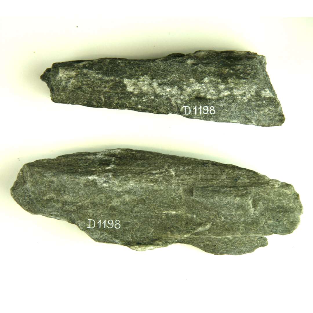 To fragmenter af stangformede hvæssesten af lysegrå sandsten. Begge stykkers form er meget uregelmæssige med rå afspaltningsflader og kun den ene sten udviser et større tilslebet overfladeområde. Længde henholdsvis: ca. 14 og 16,3 cm.
