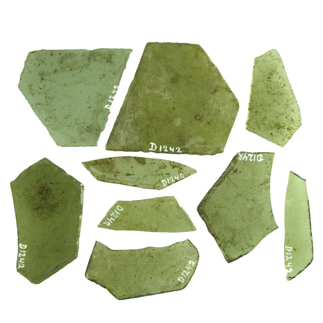 To hele ruder af klart grønligt glas med afnappede kanter af form som rhombe med afskåret spids. Rudernes største længde er henholdsvis ca. 7,5 og 8,9 cm., bredden 7,5 og 8,6 cm. Syv rudefragmenter af klart grønligt glas med afnappede kanter antagelig fra ruderne af rhombeform med afskåret spids.