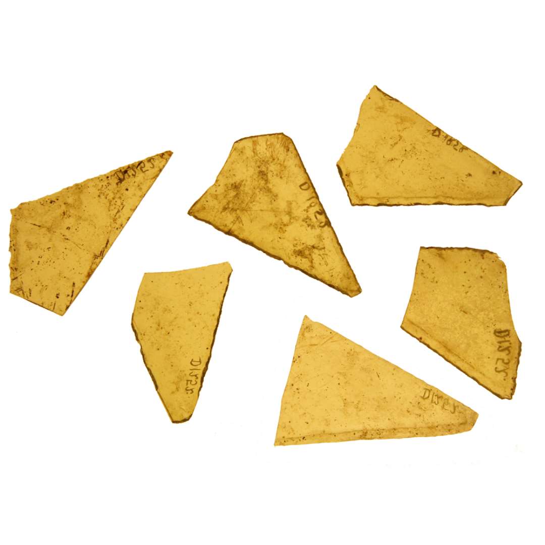 214 fragmenter af klart, grønligt glas, med tildels afknappede kanter fra ruder dels i form af ligebenede, spidsvinklede trekanter, dels i form af skæve spidsvinklede trekanter.