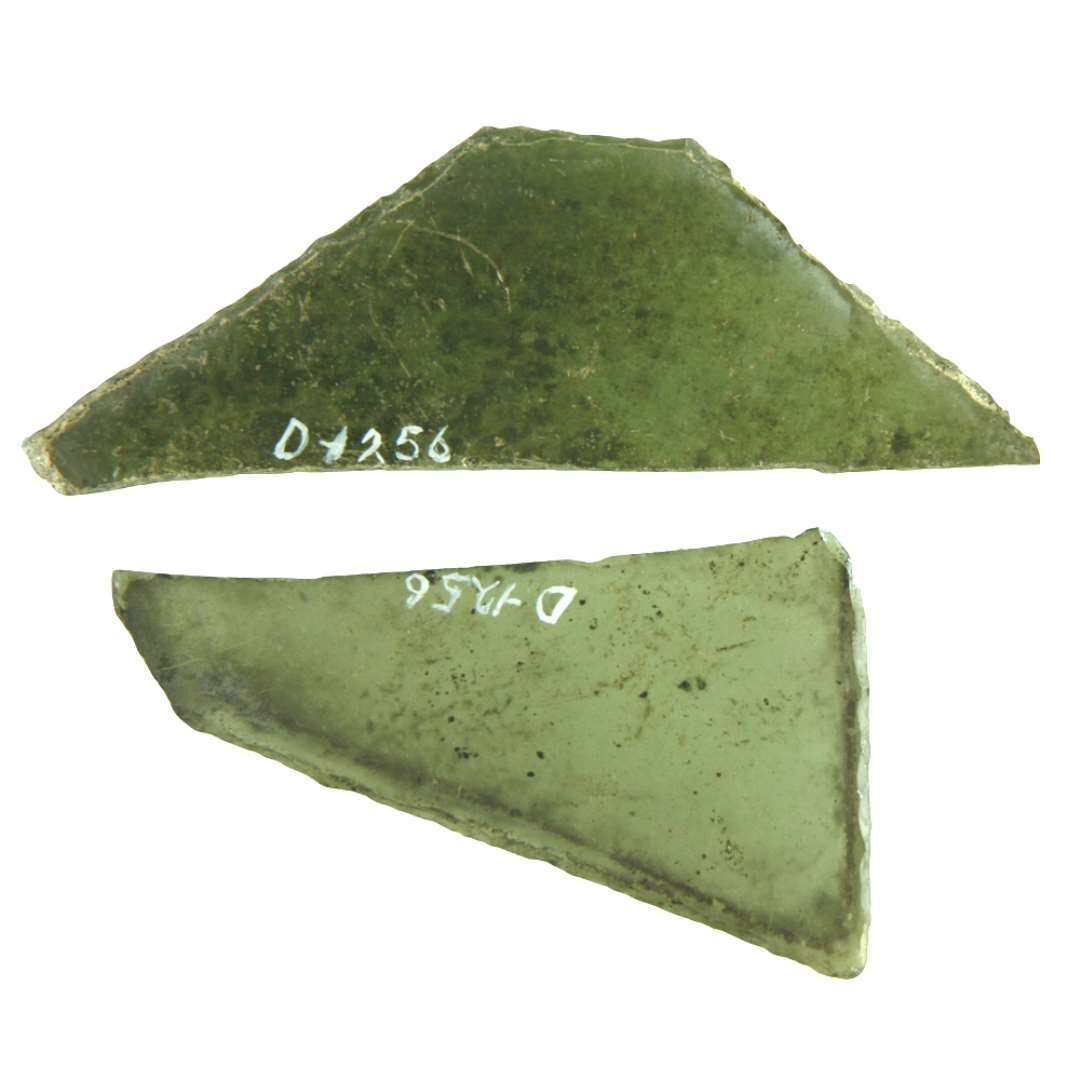 2 rudefragmenter af klart, grønligt glas med afnsppede kanter. Fragmenterne udviser 2 stumpe og en spids vinkel. Antagelig fra rude i sekssidet, rhombeagtig form. Største mål: 8 x 10,3 cm. 
