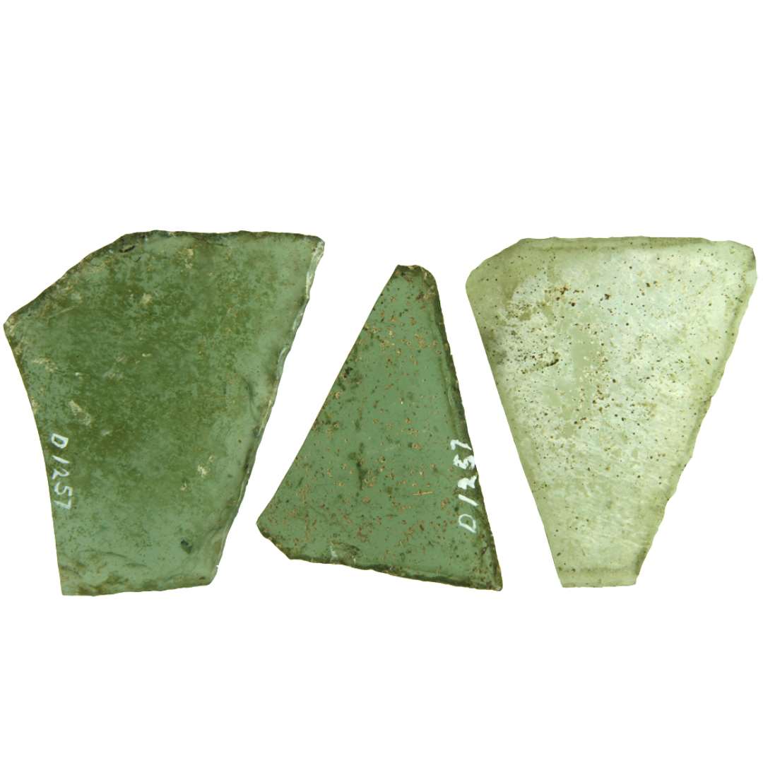 3 rudefragmenter af klart, grønligt glas med afnappede kanter. Fragmenterne udviser alle 2 stumpe og en spids  vinkel og hidrører antagelig fra ruder af 5-sidet form. Største mål henholdsvis 6,8 x 8,8 cm. - 5 x 6,3 cm, - 5,8 x 7,2 cm. Det største af rudefragmenterne er fremstillet af en omtrent ½ cm. tyk glasskive.