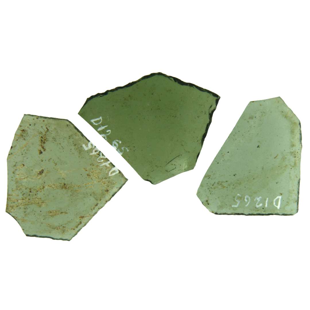 3 rudefragmenter af klart, grønligt glas med delvis afnappede kanter. Fragmenterne hidrører antagelig fra ruder af aflang 6 sidet form, men er overbrudt på midten. Største bredde henholdsvis: 4 cm. 4,6 cm. 4,9 cm, Længde: 5,3 cm. 4,65 cm. 4,4 cm.