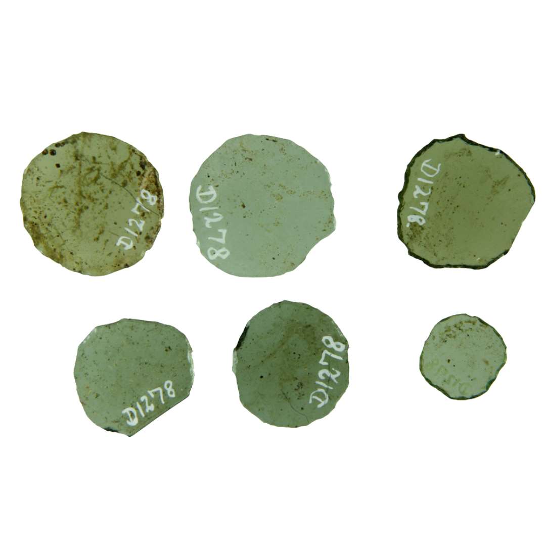 6 hele ruder af klart grønlig glas med afnappede kanter. Ruderne er tilnærmelsesvis cirkulære, ofte ret ujævne i kanterne. En enkelt rude mangler ca. 1/5 af cirkelrundingen, idet det manglende afsnit begrænset af glaspladens naturlige afrundede kant. Rudernes diameter er ca.  1,8 - 2,6 - 2,7 - 2,8 - 3,0.