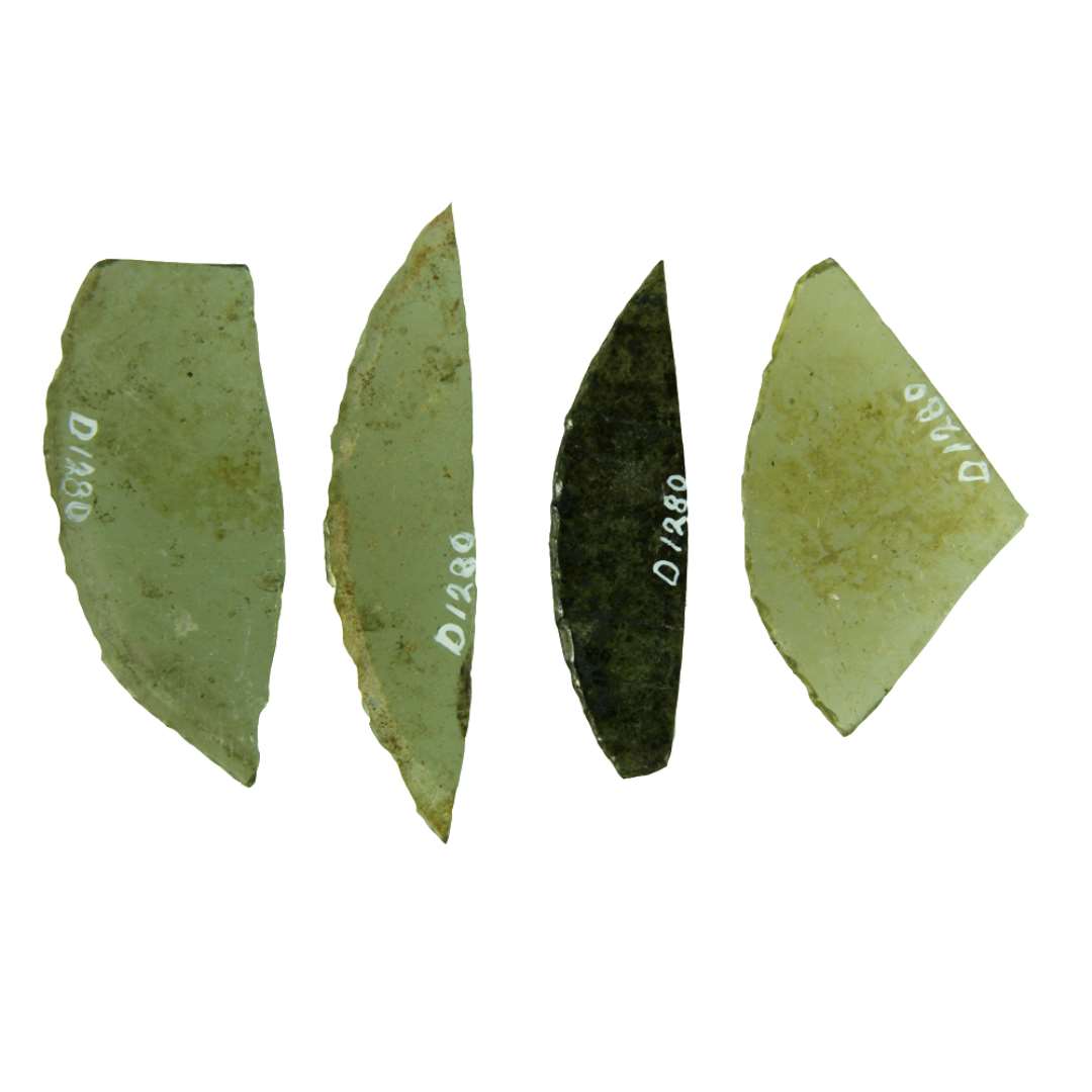 15 rudefragmenter af klart grønligt glas med afnappede kanter. De hidrører fra ruder af cirkulær form og udgør alle større eller mindre cirkelafsnit, ofte afbrudt i den ene eller begge ender.  Kordelængden varierer fra: ca. 3,5 - 8,4 cm.