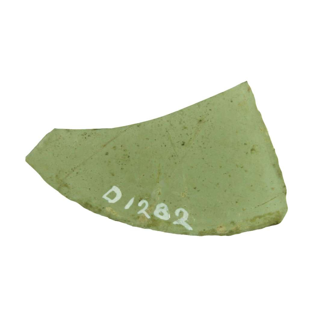 1 rudefragment af klart grønligt glas med afnappede kanter. Hidrører antagelig fra rude af form som cirkeludsnit med en centrums vinkel på ca. 60 grader.  Kordelængden ca.  5,5 cm.