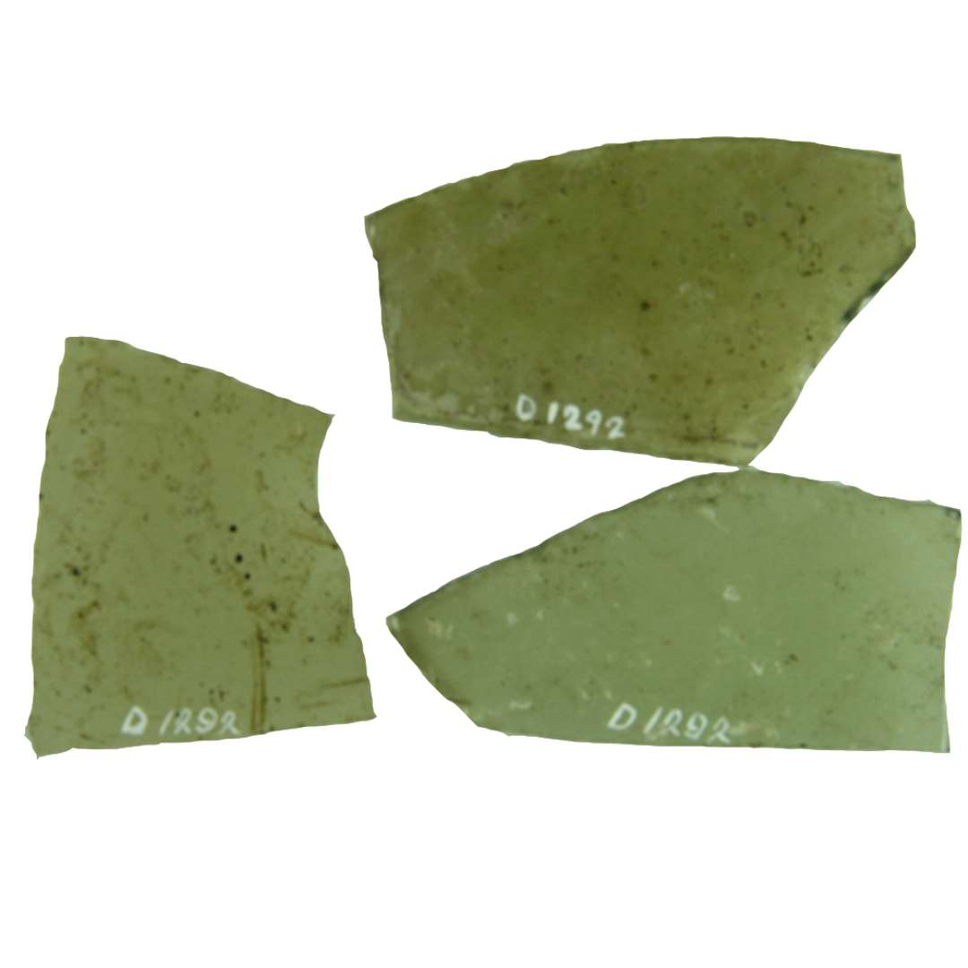 20 fragmenter af klart grønligt glas med afnappede kanter. Hidrører fra ruder af ikke nærmere bestemmelig, mangesidet form. Flere af ruderne kendetegnes ved et spidsvinklet eller stumpvinklet hjørne. Dimensioner fra 2,4 x 3,9 cm. til 5,4 x 6,2 cm.