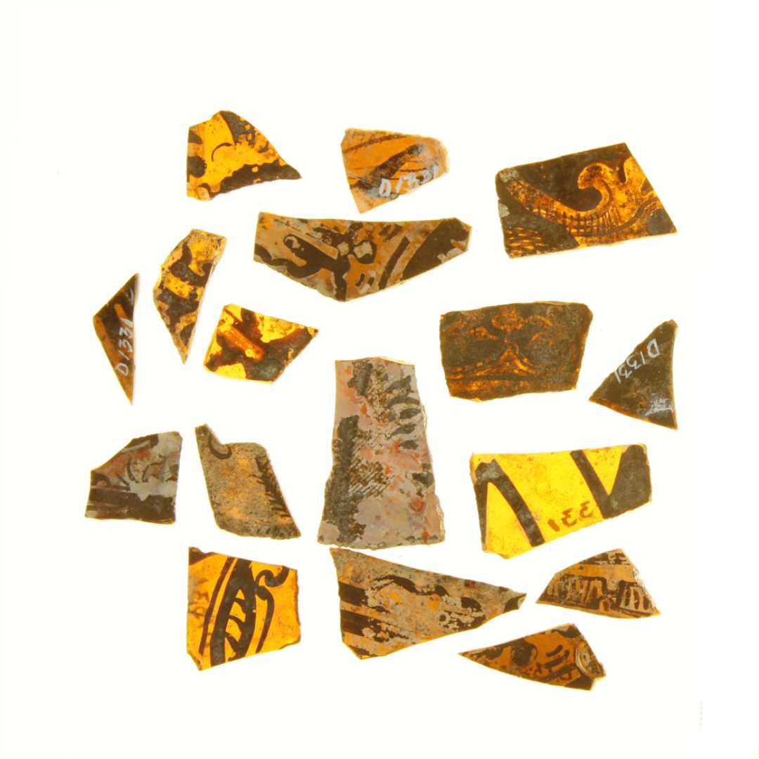22 fragmenter af ruder af gult glas med afnappede kanter og med påmalede stiliserede plantemotiver og stregornamenter i brune farver. Rudernes form lader sig ikke bestemmes med sikkerhed, trapezform eller krum rektangulær form.