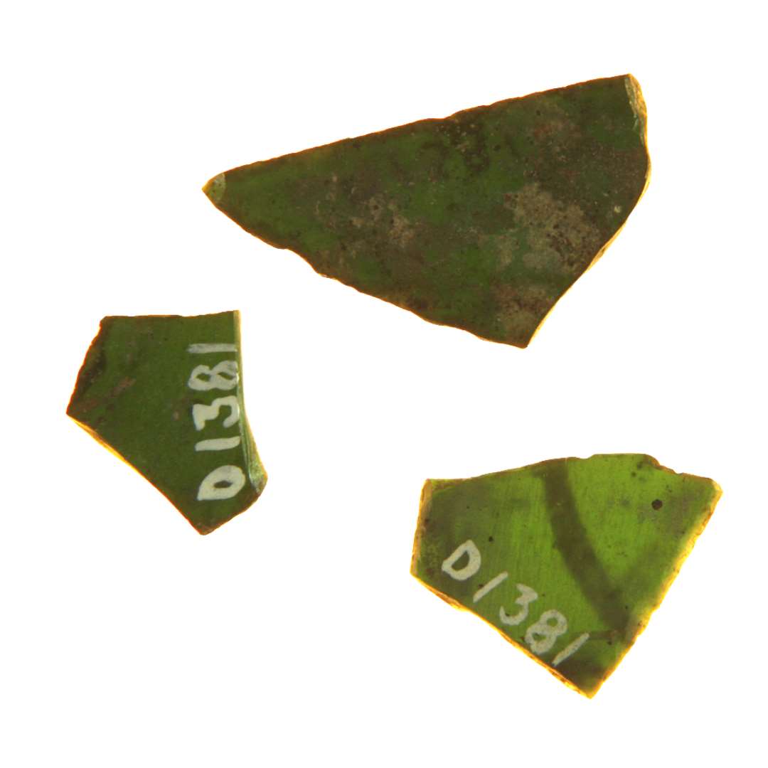 3 fragmenter af ruder af dybgrøn glas med afnappede kanter bemalet i en art stregmønster med en nu afskallet farve. Hidrører antagelig fra rude af form som retvinklet trekant, hvis længste side danner en jævn udadbugning. Krumning. Fragmentets største mål: 