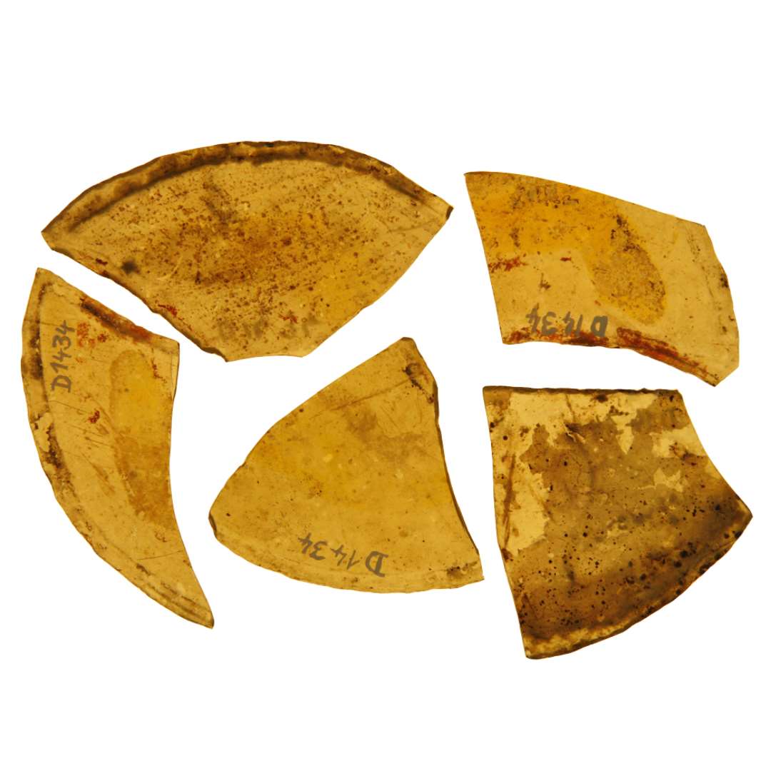 7 fragmenter af anseelige ruder af klart grønligt glas med afnappede kanter. Rudernes form har været nærmest halvcirkulær, de 2 med lige, de 5 med konkav diameterlinie. Alle har tilsyneladende været dekoreret med plantemotiver af nær beslægtet type i næsten hel afskallede brune, rødlige og gule farver, hvoraf  kun enkelte rester er bevaret. Langs den halvcirkulære yderrand har ornamenterne været indrammet af koncentriske, tynde cirkelstriber.  Rudernes længde (diameterlinier) har været omkring 10 cm., højden omkring 5 cm.