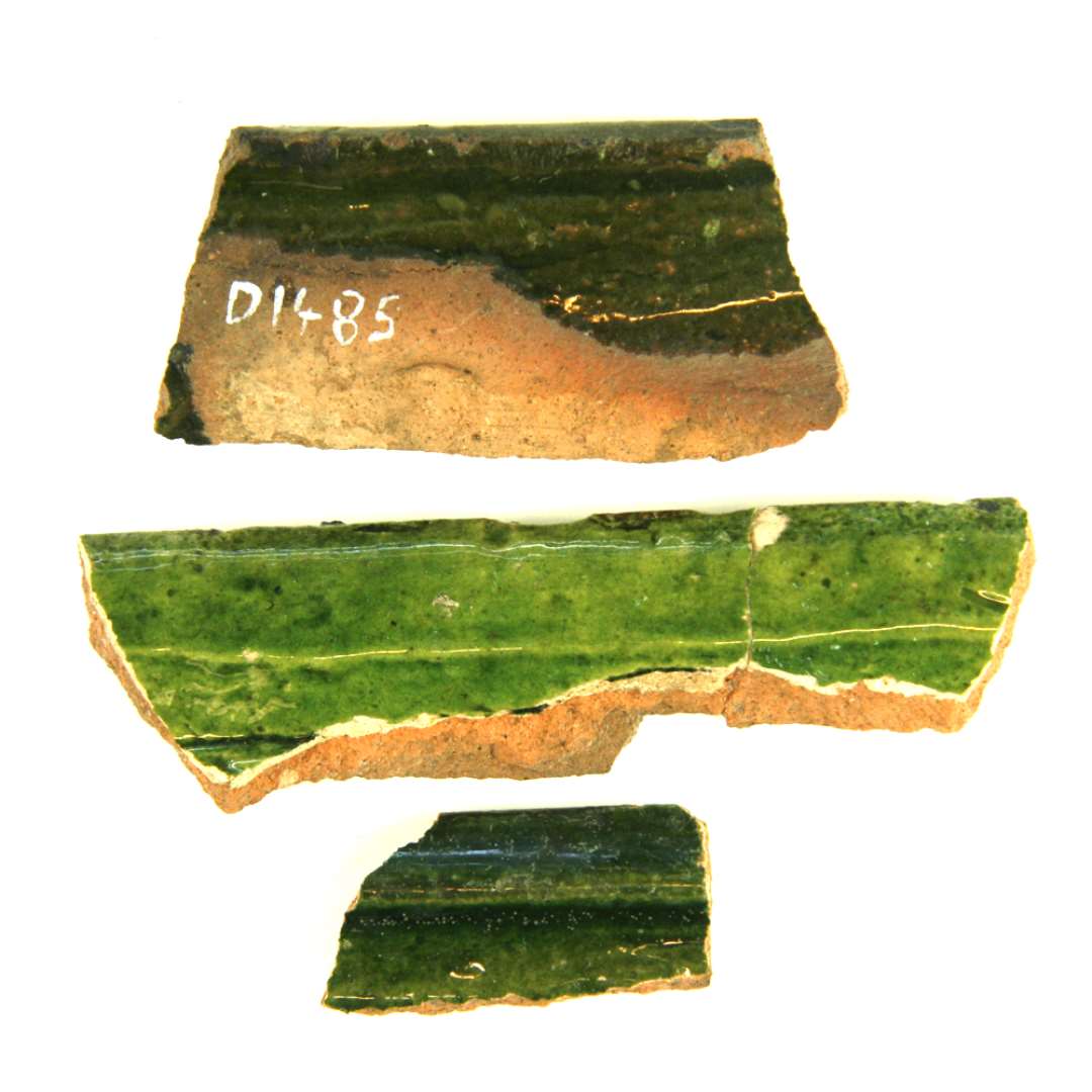 Tre fragmenter af kakkelramme af rødbrændt lergods. De to af fragmenterne har på ydersiden belægning af pibelersbegitning og alle er dækket af grønlig blyglasur.