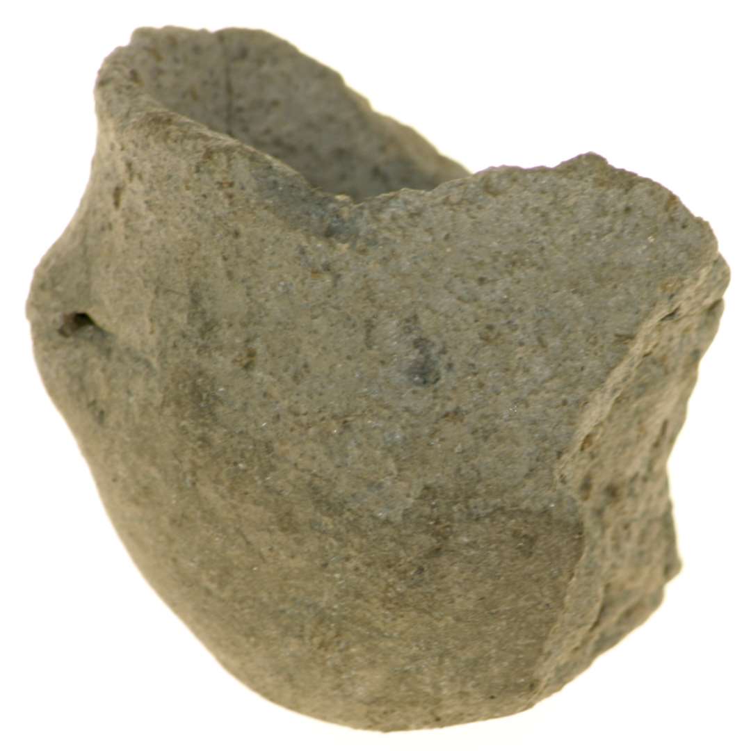 Fragment af et lille lerbæger. Tykvægget, med ujævn bund. På de ene skulder et lille vandret gennemstukket øre. Højde: 4,5 cm., mundingsdiameter: 4,5 cm.

miniature miniaturekar