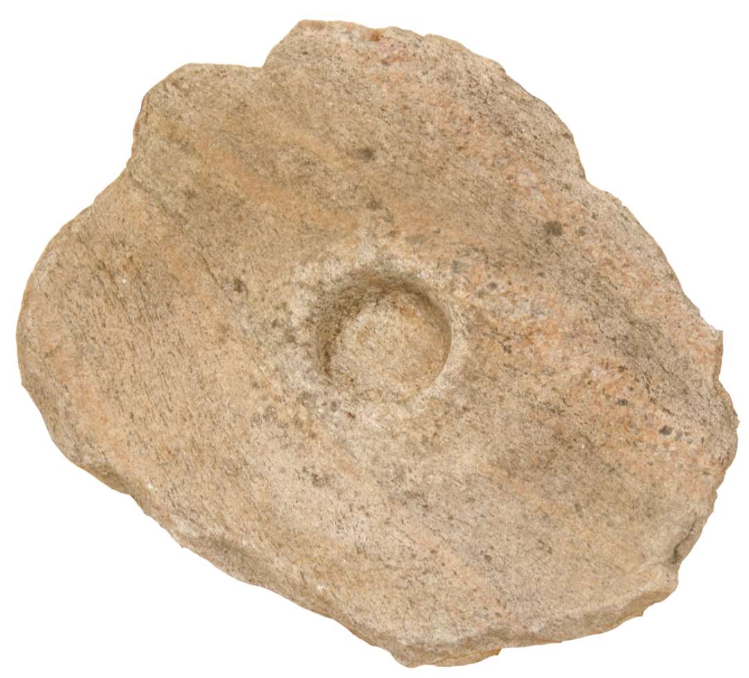 Kværnsten af svær sandsten. På den ene side meget slidt, og i midten en rund fordybning i et noget ophøjet parti. Fordybningens diameter: 9 cm. 49 x 40 x 23 cm. 