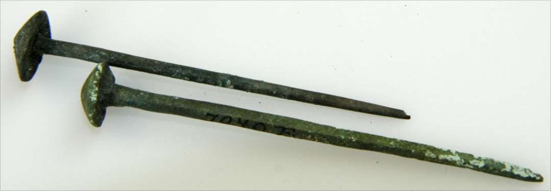 Bronzenåle. Bestående af stilk med skiveformet hoved med hvælvet overside. Længde: h.h.v. 7 og 8 cm.