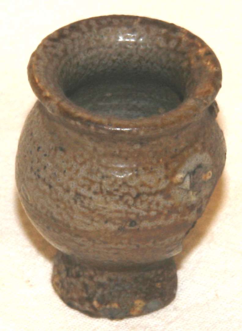 Krukke af brændt ler med glasur. Højde: 4 cm., bredde over mundingen: 2,5 cm.

Salvekrukke