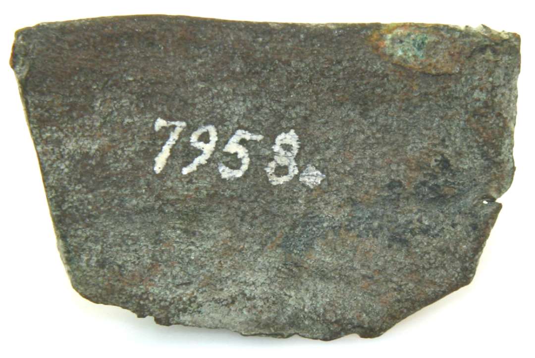 Fragment af kobberlegering, milugvis fra randen af metalkar. Mål: 3,2 x 5,2 cm.