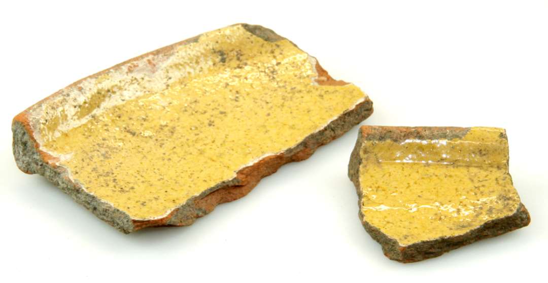 To randskår af rødbrændt lerfad med indvendig, gul glasur. Mål h.h.v.: 8x4,5 og 3,5x3,5 cm.
