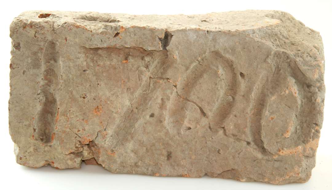 Mursten af rødbrændt tegl med indridset årstal 1700. Et stykke slået af den ene side. Mål: 25,5 x 13 x 7,5 cm.