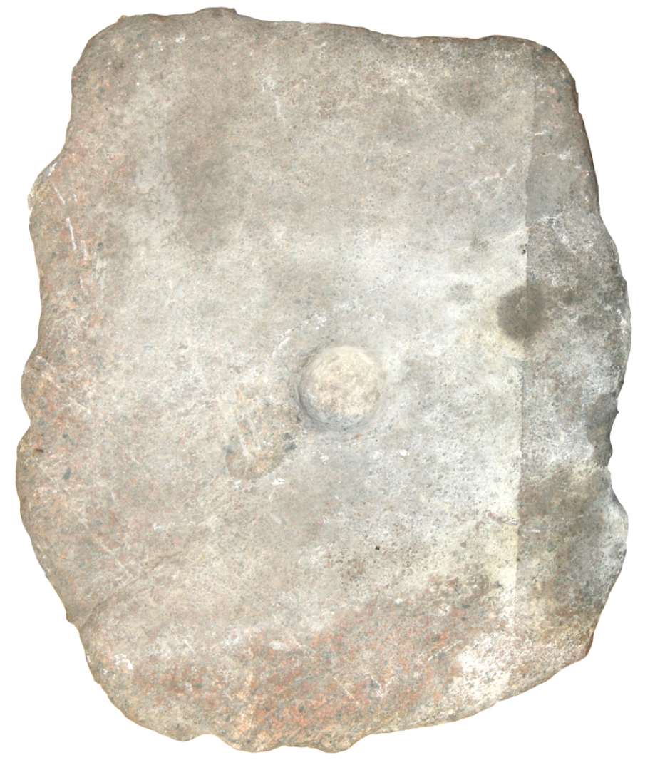 Kvænsten af granit. Mål: 43 x 37 x 13 cm. På den fladslidte side en lille rund fordybning. Diameter: 5 cm.