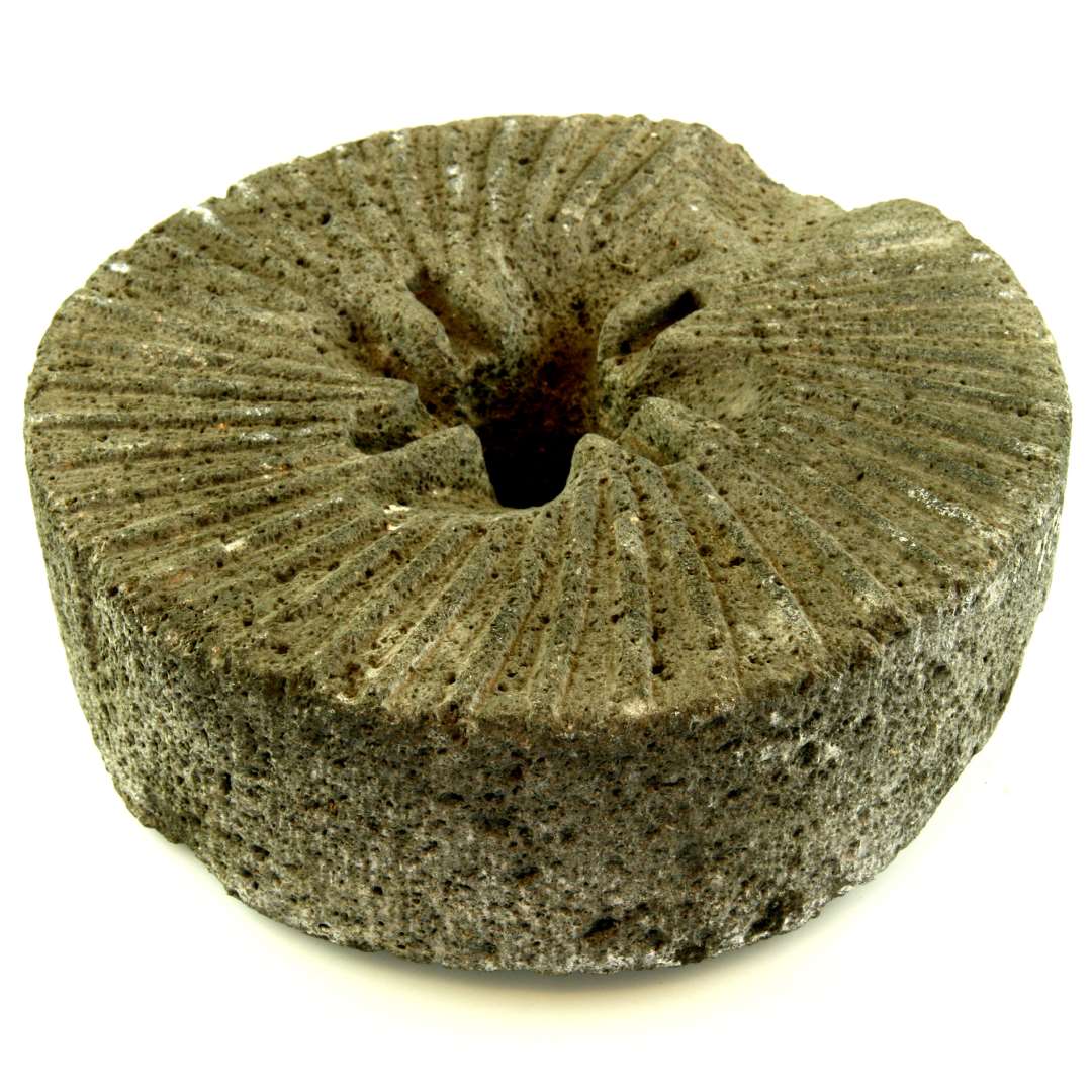 Kværnstensløber af basalt. Rillehugget på undersiden; i midten et rundt hul, diameter: 4 cm, hvorfra på undersiden er hugget riller ud til bærejernet. Mål: højde 8 cm., diameter 23 cm.