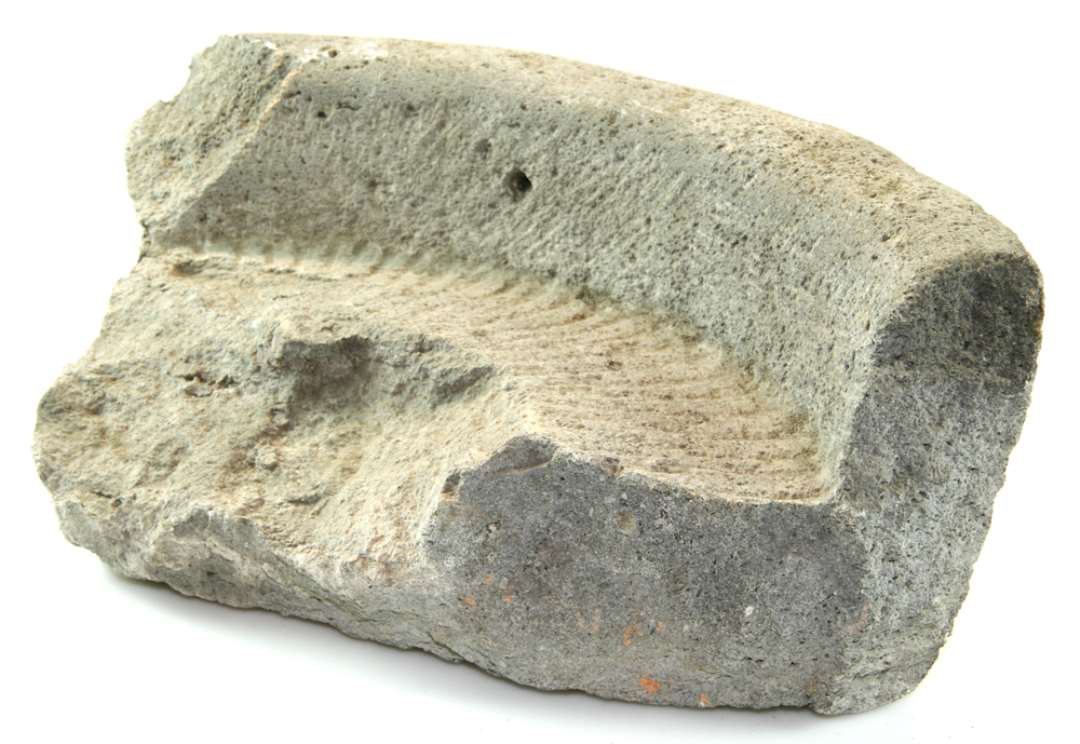Fragment af kværnstensligger af basalt. Kummeform, rillehugget bund. Mål: højde 14 cm., størrelse 34 x 18 cm.
