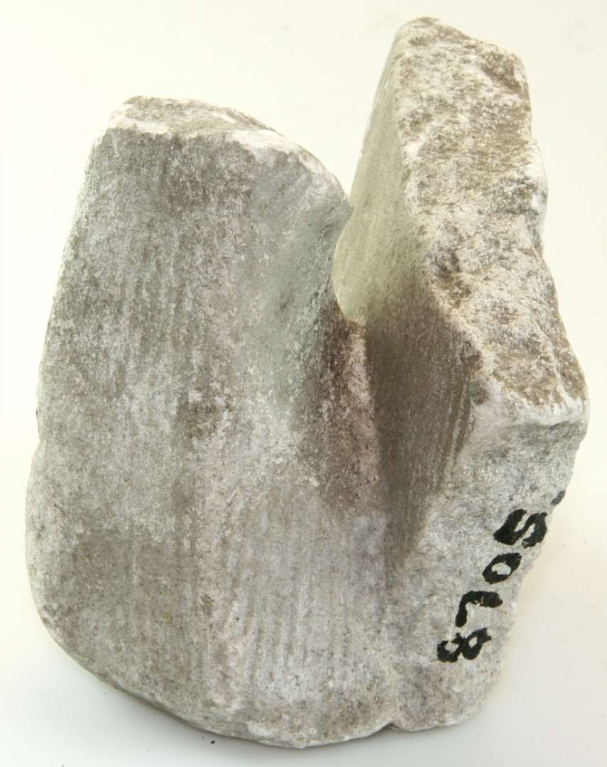 Fragment af morter af kalk-sandsten. Det nederste af hank med lidt af kummevæg. Mål: 12 x 11 x 10 cm.