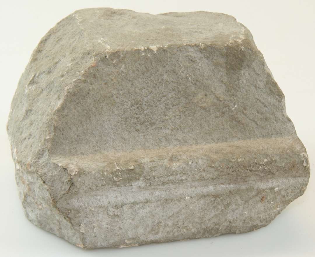 Gesimssten af sandsten. Højde 8,5 cm., længde 13,5 cm., bredde 10 cm.